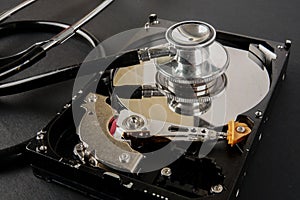 RECOVERY AND REPAIR TECHNOLOGY CONCEPT: Hard Disk Drive HDD with stethoscope isolated on a black background.