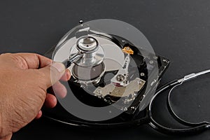 RECOVERY AND REPAIR TECHNOLOGY CONCEPT: Hard Disk Drive HDD with stethoscope isolated on a black background.