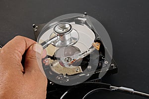 RECOVERY AND REPAIR TECHNOLOGY CONCEPT: Hard Disk Drive HDD with stethoscope isolated on a black background.