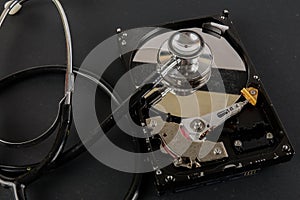 RECOVERY AND REPAIR TECHNOLOGY CONCEPT: Hard Disk Drive HDD with stethoscope isolated on a black background.