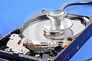 RECOVERY AND REPAIR TECHNOLOGY CONCEPT: Hard Disk Drive HDD with stethoscope isolated on a blue background.