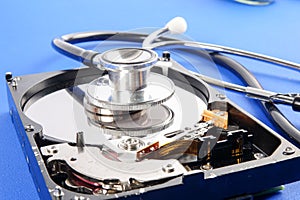 RECOVERY AND REPAIR TECHNOLOGY CONCEPT: Hard Disk Drive HDD with stethoscope isolated on a blue background.