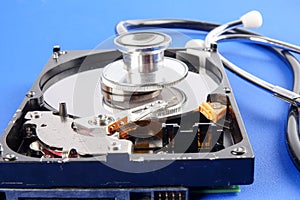 RECOVERY AND REPAIR TECHNOLOGY CONCEPT: Hard Disk Drive HDD with stethoscope isolated on a blue background.