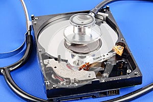 RECOVERY AND REPAIR TECHNOLOGY CONCEPT: Hard Disk Drive HDD with stethoscope isolated on a blue background.