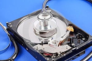 RECOVERY AND REPAIR TECHNOLOGY CONCEPT: Hard Disk Drive HDD with stethoscope isolated on a blue background.