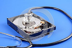 RECOVERY AND REPAIR TECHNOLOGY CONCEPT: Hard Disk Drive HDD with stethoscope isolated on a blue background