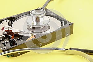 RECOVERY AND REPAIR TECHNOLOGY CONCEPT: Hard Disk Drive HDD with stethoscope isolated on a yellow background.