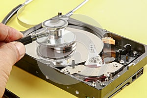 RECOVERY AND REPAIR TECHNOLOGY CONCEPT: Hard Disk Drive HDD with stethoscope isolated on a yellow background.