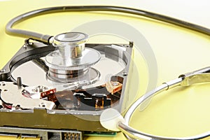 RECOVERY AND REPAIR TECHNOLOGY CONCEPT: Hard Disk Drive HDD with stethoscope isolated on a yellow background.