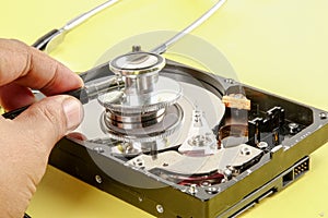 RECOVERY AND REPAIR TECHNOLOGY CONCEPT: Hard Disk Drive HDD with stethoscope isolated on a yellow background.