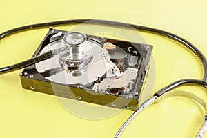 RECOVERY AND REPAIR TECHNOLOGY CONCEPT: Hard Disk Drive HDD with stethoscope isolated on a yellow background.