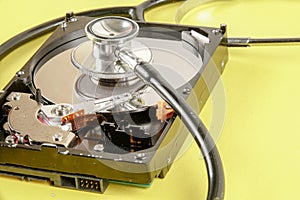 RECOVERY AND REPAIR TECHNOLOGY CONCEPT: Hard Disk Drive HDD with stethoscope isolated on a yellow background.