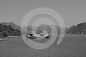 Recreation on the boat near the shore of a mountain. Ship on the water. summer vacation. black and white