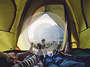 Recreation at mountain in camping tent.group of feet lying down inside tent with mountain view in sunset with friend