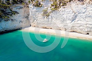 Recreation small boat in beautiful gulf with turquoise water. Faraglioni sea stacks in Puglia, Baia delle Zagare