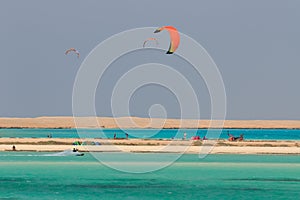 Recreational activity, water sports, action, hobby and fun in summer time. Kite boarding sport, kiting people on island, blue sea