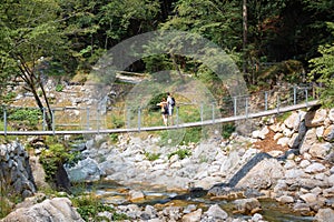 Recreational hikers couple crossing a suspension bridge