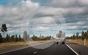 Recreational vehicle with bike hanging on the rear driving through the countryside. Travel and wanderlust concept image with copy photo