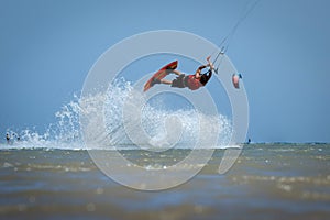 Recreational water sports: kitesurfing. Kiteboarding sportsman jumping high in the sky on windy day. Extreme sports action