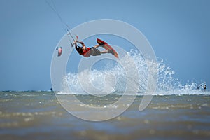 Recreational water sports: kitesurfing. Kiteboarding sportsman jumping high in the sky on windy day. Extreme sports action