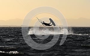 Recreational water sports: kitesurfing. Kiteboarding sportsman jumping high in the sky on windy day. Extreme sports action