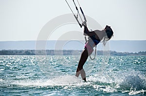 Recreational water sports: kitesurfing. Kiteboarding sportsman jumping high in the sky on windy day. Extreme sports action