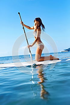 Recreational Water Sports. Woman Paddling On Surf Board. Summer