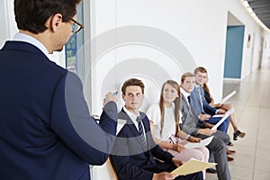 Recruiter addressing job candidates waiting for interviews