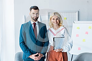 Recruiter with clenched hands and blonde woman with clipboard standing in office