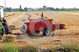 Rectangular baler discharges straw bale in a field during the harvesting process