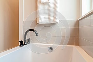 Rectangular bathtub of home bathroom with black curved faucet on the rim