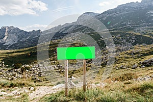 Rectangular blank sign on the roadside with mountains in the background