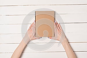 Rectangular box in female hands. Top view. White table on the background