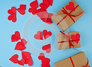 Rectangular box is wrapped in brown paper and tied with a red thin silk ribbon on a blue background