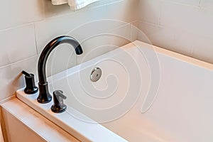 Rectangular built in bathtub inside bathroom of a home with white tiles wall