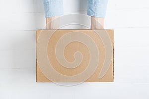 Rectangular cardboard box in female hands. Top view, white background