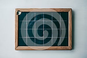 Rectangular chalkboard with grid pattern in wooden frame, slight wear and small hole
