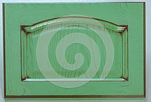 Rectangular dark green kitchen facade close-up. Background of turquoise wooden decorative element