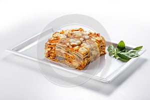 Rectangular dish with eggplant parmigiana with tomato cheese and basil leaves