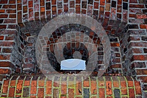 Rectangular embrasure with semicircular arch with recesses of several levels laid out of red brick which looks to piece of blue