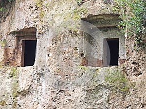 The rectangular entrances to Etruscan tombs carved in the wall of a tufo cliff photo