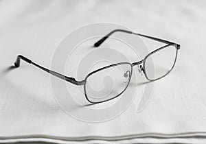 Rectangular eyeglasses with thin black metal frames rest on a