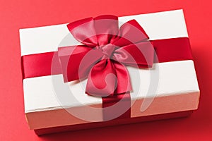 Rectangular gift box with a bow on a red background, close-up