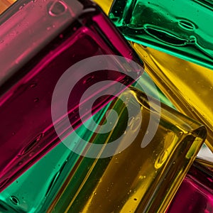 Rectangular glass blocks in vibrant magenta, teal, and yellow intersect diagonally photo