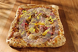 Rectangular gourmet pizza with sausage and colorfu