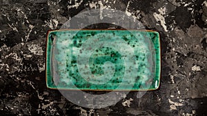 A rectangular green ceramic plate on a concrete black-and-white background. space for text. top view