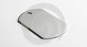 Rectangular metallic dog tag with rounded edges, lying on a white surface. The tag features a