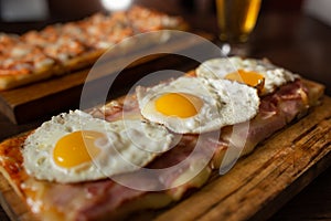 Rectangular pizza in an Argentinian restaurant with mozzarella, bacon and fried eggs