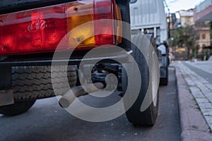 rectangular red and yellow back light and exhaust pipe of a parked vehicle from behind in city low angle