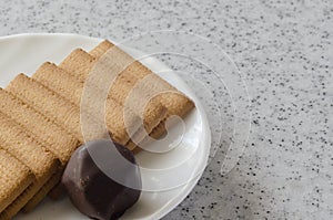 Rectangular shortbread cookies and chocolates on a white saucer